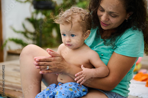 Mother holding her young child outdoors, both enjoying quality time together on a wooden deck photo