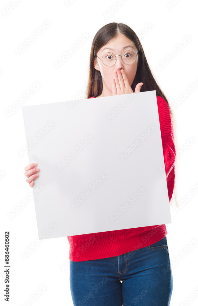 Young Chinese woman over isolated background holding blank banner cover mouth with hand shocked with shame for mistake, expression of fear, scared in silence, secret concept Young Chinese woman over isolated background holding blank banner cover mouth with hand shocked with shame for mistake, expression of fear, scared in silence, secret concept