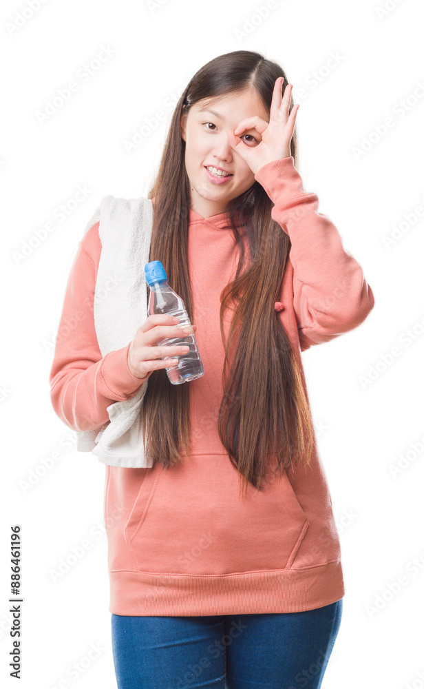 Young Chinese woman over isolated background wearing sport sweathshirt with happy face smiling doing ok sign with hand on eye looking through fingers Young Chinese woman over isolated background wearing sport sweathshirt with happy face smiling doing ok sign with hand on eye looking through fingers