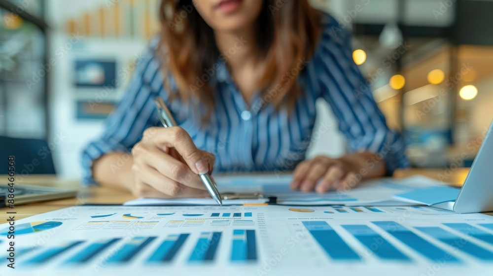 Fototapeta premium Businesswoman analyzing financial reports and statistics at the office desk. Professional working on data analysis and market research.