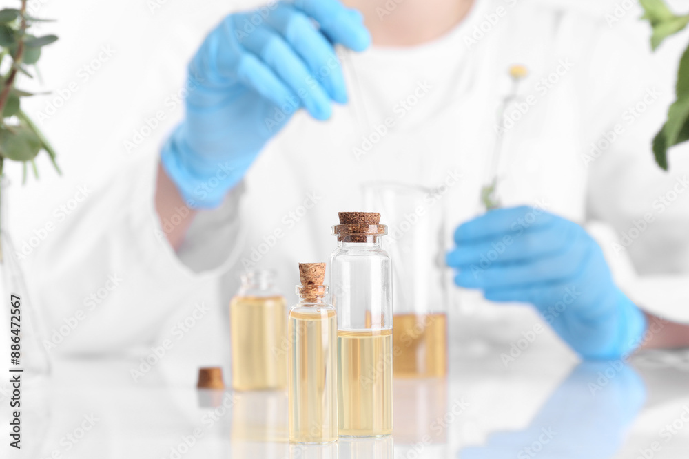 Aromatherapy product. Scientist developing essential oils at white table in laboratory, focus on bottles Aromatherapy product. Scientist developing essential oils at white table in laboratory, focus on bottles