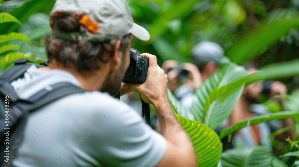 Fototapeta premium A nature photographer stands in a tropical forest filled with dense vegetation, capturing the beauty and diversity of the environment as others explore the rich ecosystem around him.