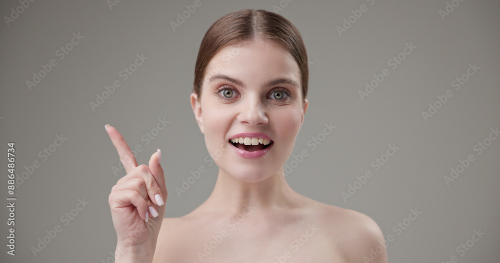 Beauty, health, cosmetics, anti-aging therapy and skin care concept - young beautiful brunette Caucasian woman looking at camera with wide eyes raising index finger up, showing gesturing idea Beauty, health, cosmetics, anti-aging therapy and skin care concept - young beautiful brunette Caucasian woman looking at camera with wide eyes raising index finger up, showing gesturing idea