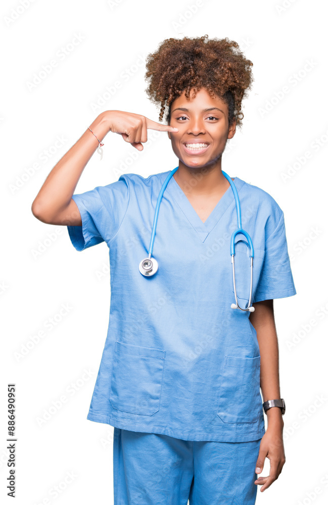 Young african american doctor woman over isolated background Pointing with hand finger to face and nose, smiling cheerful