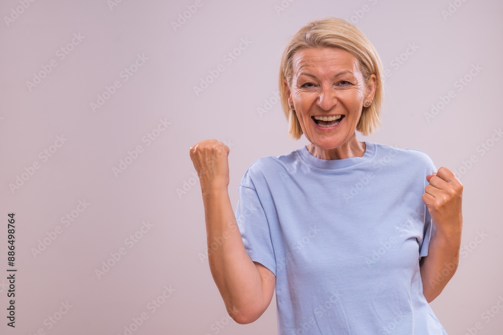 Image of happy successful mature woman celebrating on a gray background. Image of happy successful mature woman celebrating on a gray background.