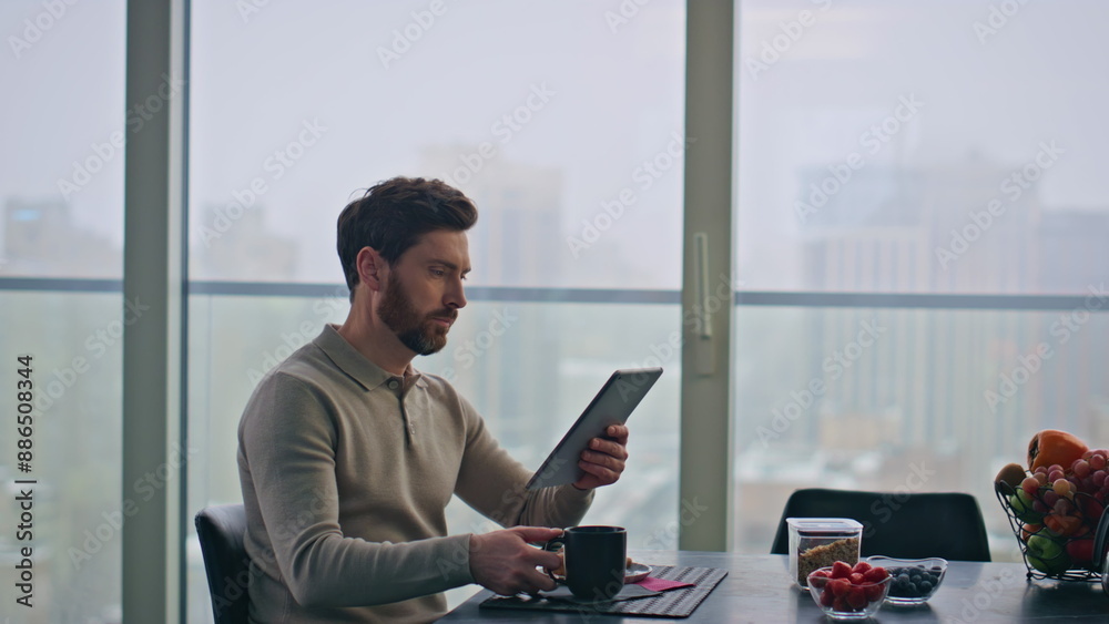 Focused freelancer chatting online looking tablet in glass apartment closeup Focused freelancer chatting online looking tablet in glass apartment closeup