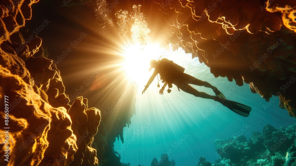 Fototapeta premium A scuba diver is pictured exploring an underwater coral reef bath in sunlight streaming down from the surface, creating a breathtaking underwater scene.