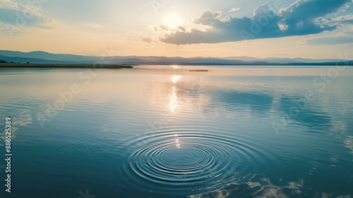 Tranquil lake at sunset with distant mountains and stone skipping waves, creating a peaceful and serene nature landscape scene. photo