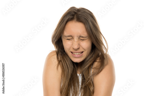 Exhausted young woman with eyes closed. Pain, stress and despair concept. White studio background.