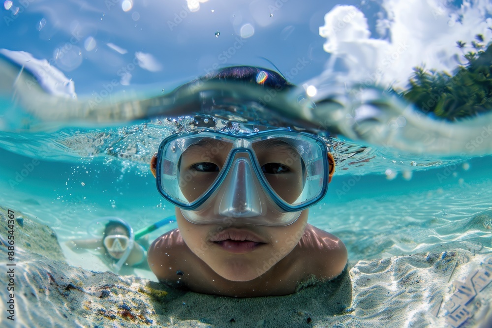 Naklejka premium A young snorkeler explores underwater wonders with their goggles, illuminated by the sun's rays revealing a serene and enchanting underwater scene.