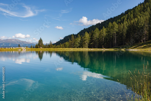 The alpine mountains reflect beautifully in the Panoramasee at Schlick2000 in the Stubai Valley, creating a serene and picturesque scene.