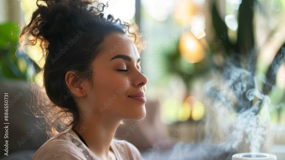 Young woman enjoying aromatherapy steam from essential oil diffuser at home Young woman enjoying aromatherapy steam from essential oil diffuser at home