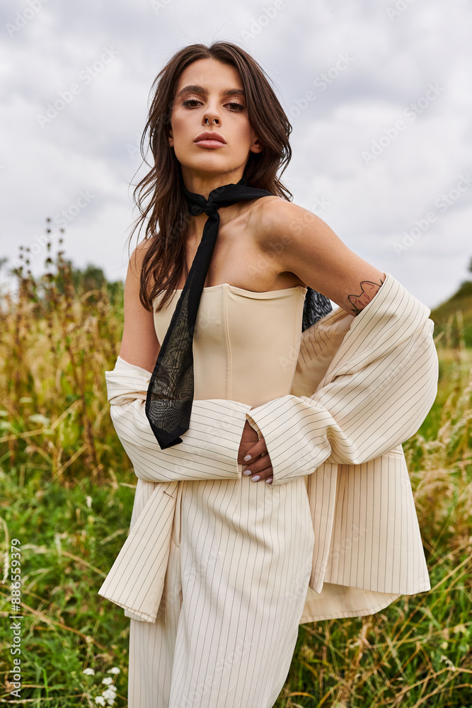 A young woman stands gracefully in a field, wearing a white corset and a black tie, soaking in the summer breeze. A young woman stands gracefully in a field, wearing a white corset and a black tie, soaking in the summer breeze.