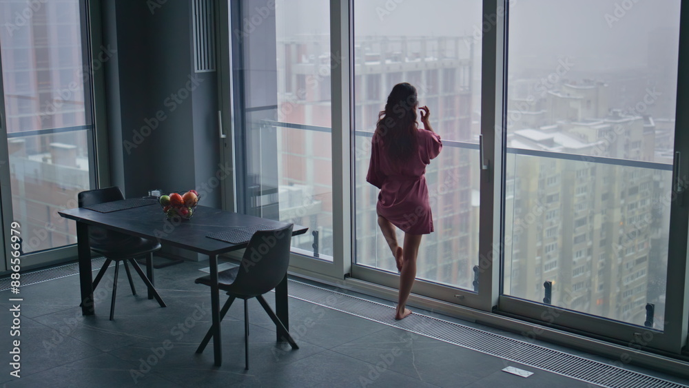 Obraz premium Morning model looking window modern kitchen back view. Domestic woman dreaming