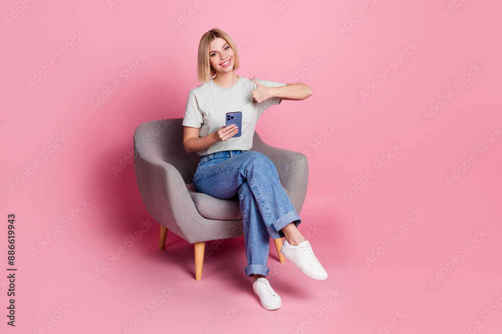 Photo of positive adorable girl wear stylish grey clothes sit comfy chair thumb up isolated on pink color background Photo of positive adorable girl wear stylish grey clothes sit comfy chair thumb up isolated on pink color background