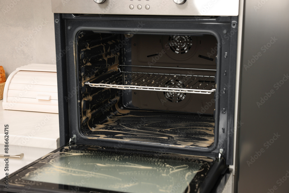 Open electric oven covered with cleaning foam in kitchen Open electric oven covered with cleaning foam in kitchen
