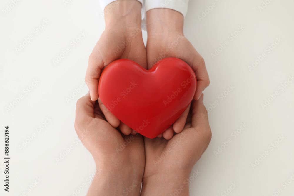 Obraz premium Doctor and patient holding red heart on white background, top view