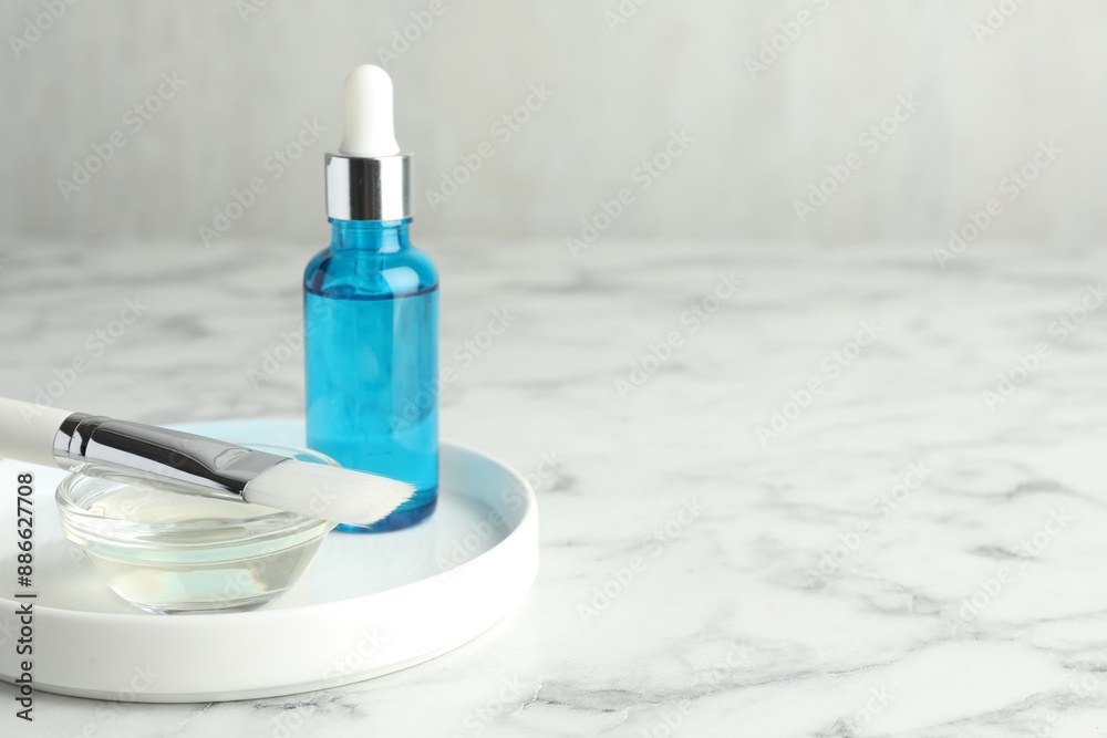 Bottle of chemical peel, bowl with liquid and brush on white marble table, space for text. Peeling procedure Bottle of chemical peel, bowl with liquid and brush on white marble table, space for text. Peeling procedure