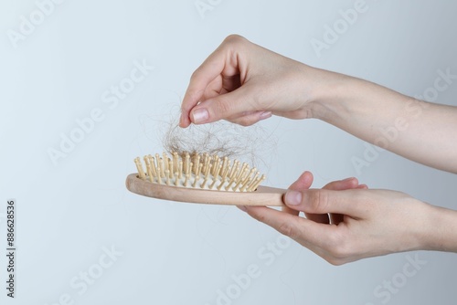 Foto Woman taking lost hair from brush on light grey background, closeup