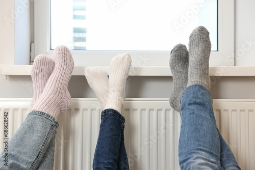 Family warming feet near heating radiator at home, closeup