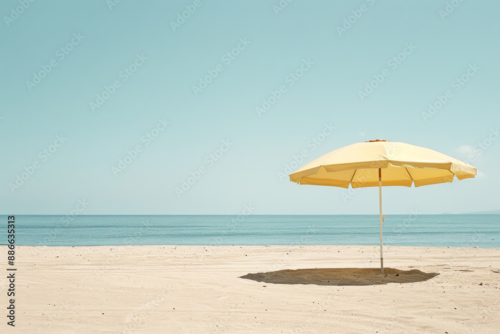 A lone yellow beach umbrella stands on an empty, sandy shore against a serene ocean backdrop A lone yellow beach umbrella stands on an empty, sandy shore against a serene ocean backdrop