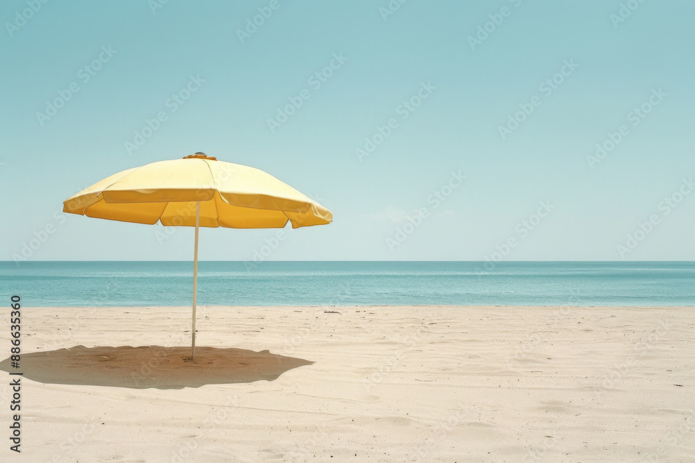 A lone yellow beach umbrella stands on an empty, sandy shore against a serene ocean backdrop A lone yellow beach umbrella stands on an empty, sandy shore against a serene ocean backdrop