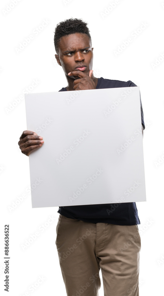 Young african american man holding a banner serious face thinking about question, very confused idea Young african american man holding a banner serious face thinking about question, very confused idea