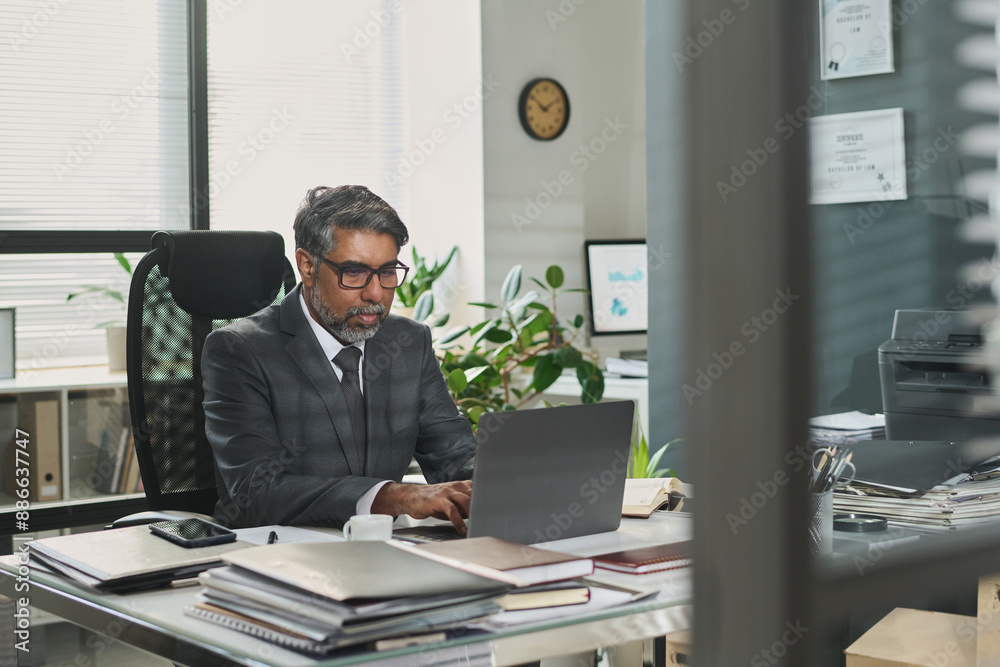 Serious male lawyer in formalwear looking at laptop screen and reading online information or electronic juridical document Serious male lawyer in formalwear looking at laptop screen and reading online information or electronic juridical document