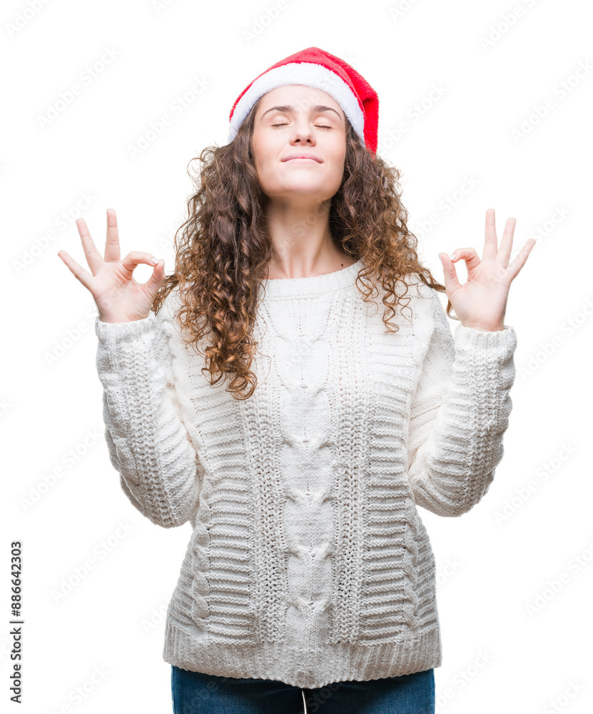 Young brunette girl wearing christmas hat over isolated background relax and smiling with eyes closed doing meditation gesture with fingers. Yoga concept. Young brunette girl wearing christmas hat over isolated background relax and smiling with eyes closed doing meditation gesture with fingers. Yoga concept.