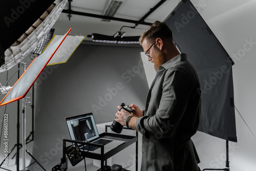 A professional photographer is reviewing camera shots in a modern studio setting