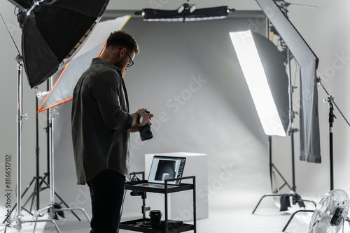 A photographer in a studio focuses on adjusting camera settings for the perfect shot