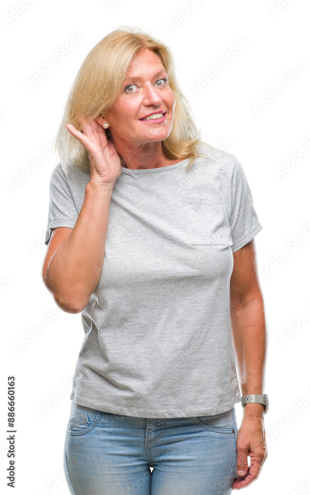 Middle age blonde woman over isolated background smiling with hand over ear listening an hearing to rumor or gossip. Deafness concept.