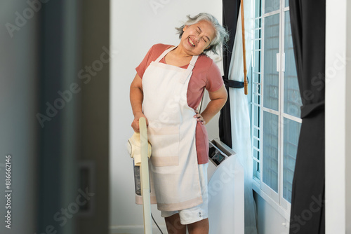 Canvas-taulu Senior woman suffering from backache, Senior woman housemaid cleaning a room, Wo