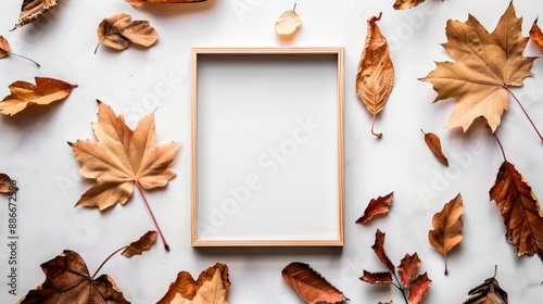 Autumn themed photo frame with dried leaves on a white flat lay surface