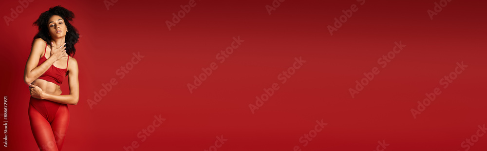 A young woman in a vibrant red top poses gracefully in a studio setting. A young woman in a vibrant red top poses gracefully in a studio setting.