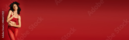Canvas Print A young woman in a vibrant red top poses gracefully in a studio setting