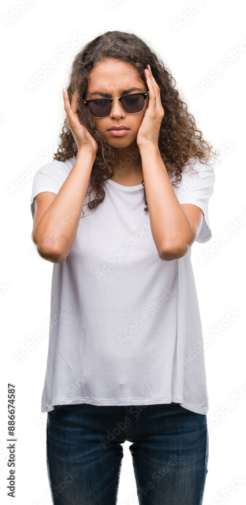 Young hispanic woman wearing sunglasses with hand on head for pain in head because stress. Suffering migraine. Young hispanic woman wearing sunglasses with hand on head for pain in head because stress. Suffering migraine.
