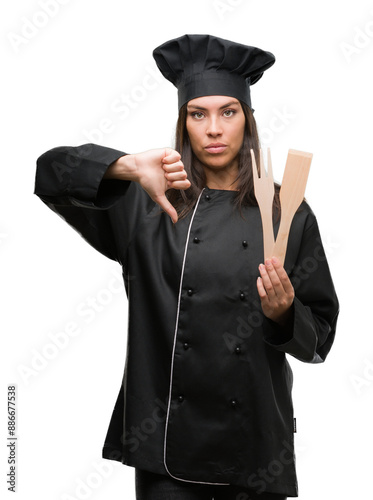 Young hispanic cook woman wearing chef uniform with angry face, negative sign showing dislike with thumbs down, rejection concept