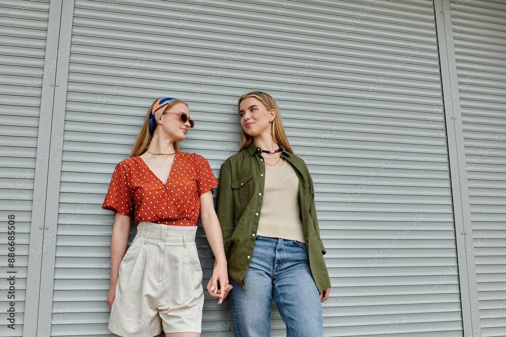 Naklejka premium A young lesbian couple shares a tender moment while strolling through a city