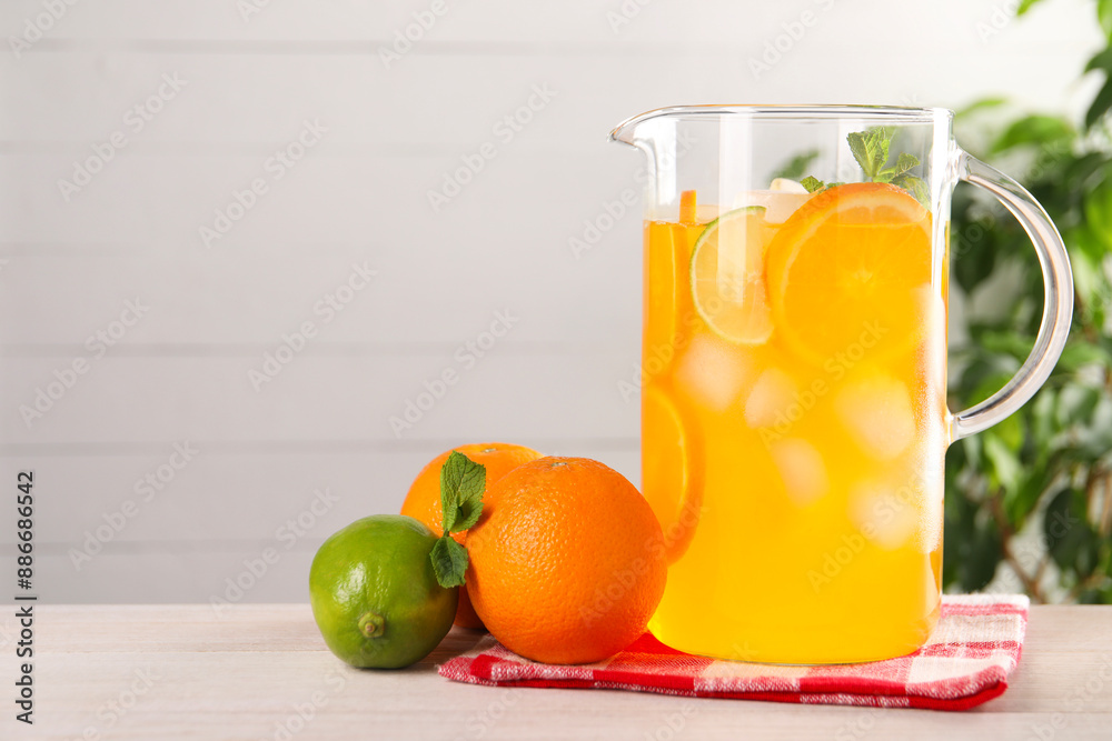 Freshly made lemonade in jug and citrus fruits on light wooden table, space for text Freshly made lemonade in jug and citrus fruits on light wooden table, space for text