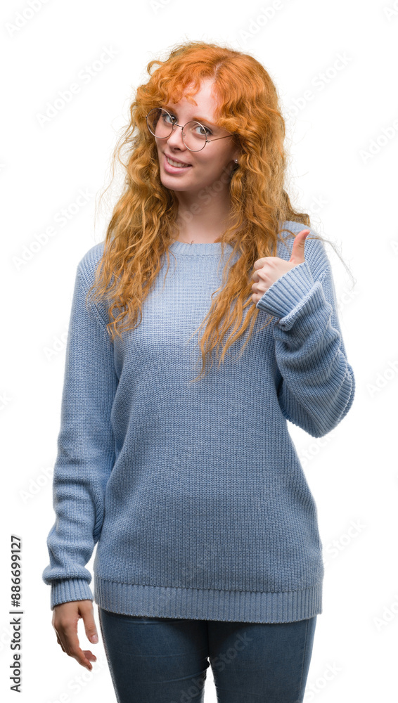 Young redhead woman wearing glasses happy with big smile doing ok sign, thumb up with fingers, excellent sign Young redhead woman wearing glasses happy with big smile doing ok sign, thumb up with fingers, excellent sign