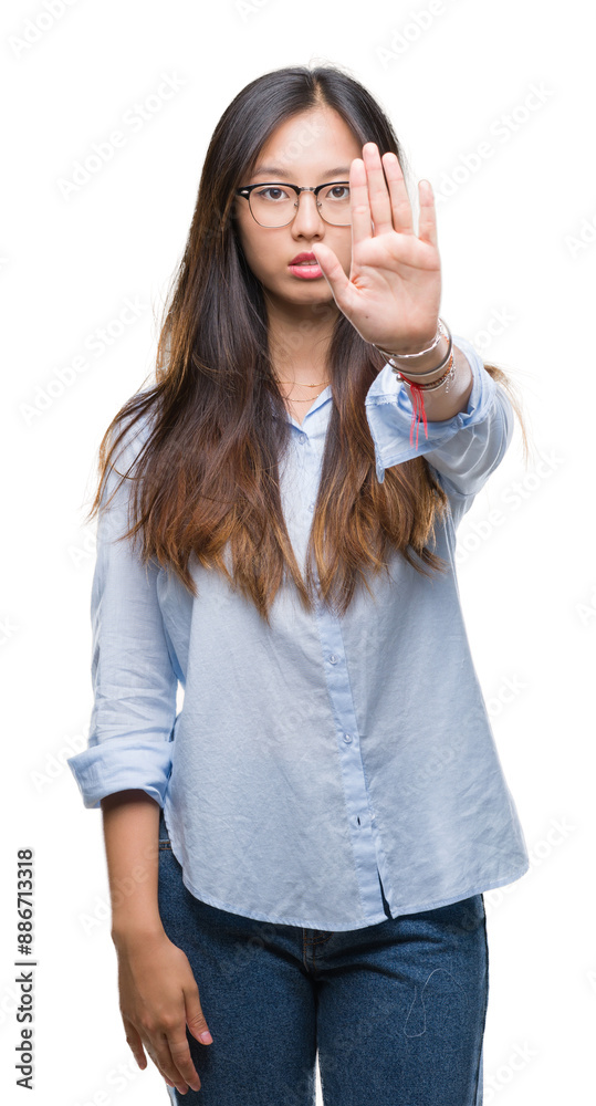 Young asian business woman wearing glasses over isolated background doing stop sing with palm of the hand. Warning expression with negative and serious gesture on the face. Young asian business woman wearing glasses over isolated background doing stop sing with palm of the hand. Warning expression with negative and serious gesture on the face.