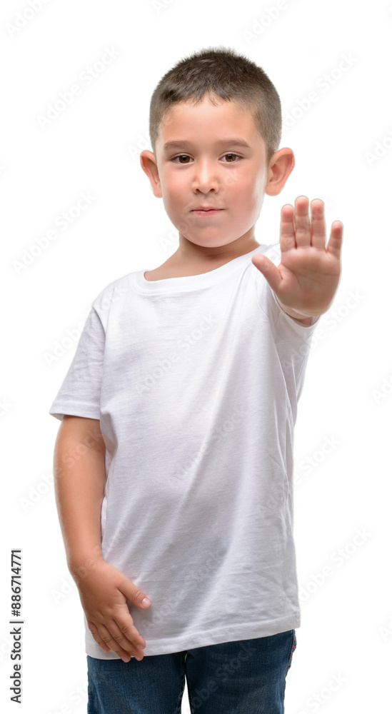 Dark haired little child with open hand doing stop sign with serious and confident expression, defense gesture Dark haired little child with open hand doing stop sign with serious and confident expression, defense gesture
