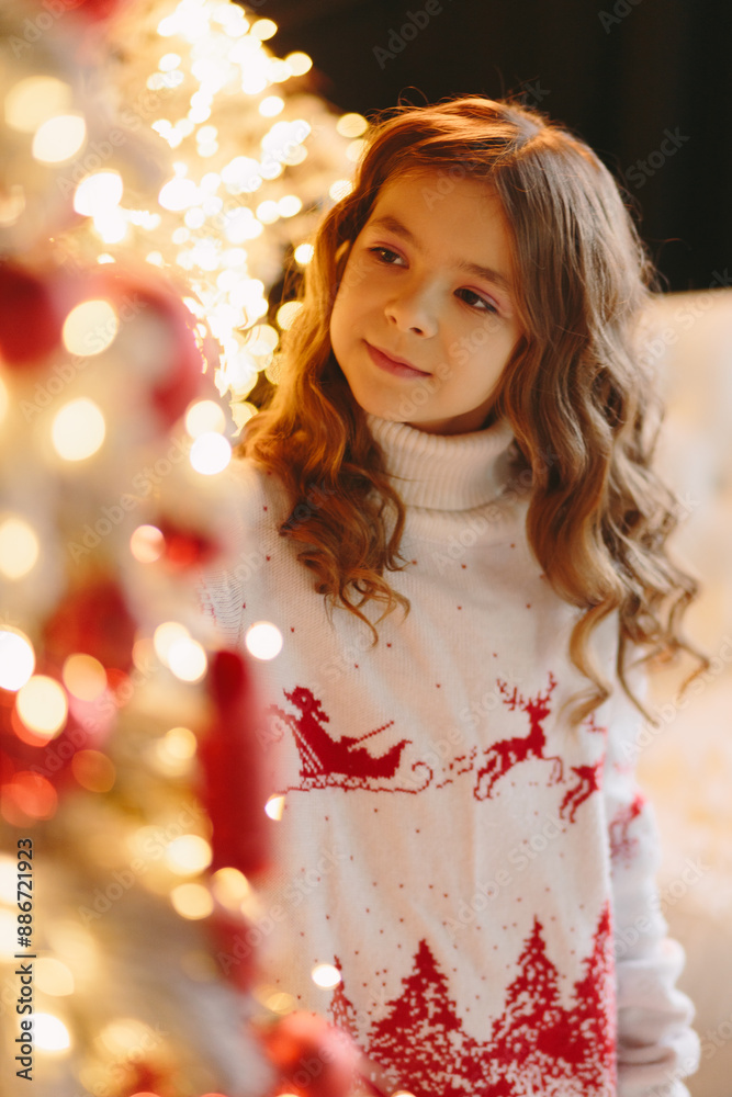 Cute girl looking at a white-red Christmas tree. Cute girl looking at a white-red Christmas tree.