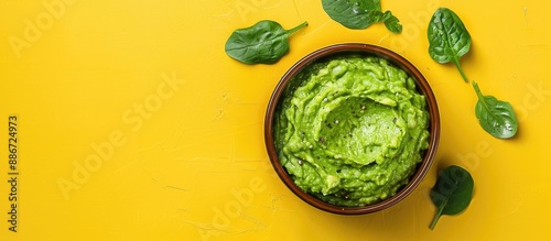 Avocado dip presented in a bowl atop a yellow backdrop with ample copy space image It is a nutritious spread made from avocados seen from a top down perspective