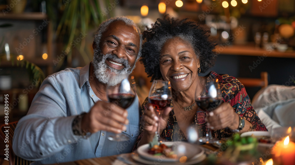 Senior couple smiling while toasting with wine glasses during a romantic dinner in their dining room Senior couple smiling while toasting with wine glasses during a romantic dinner in their dining room