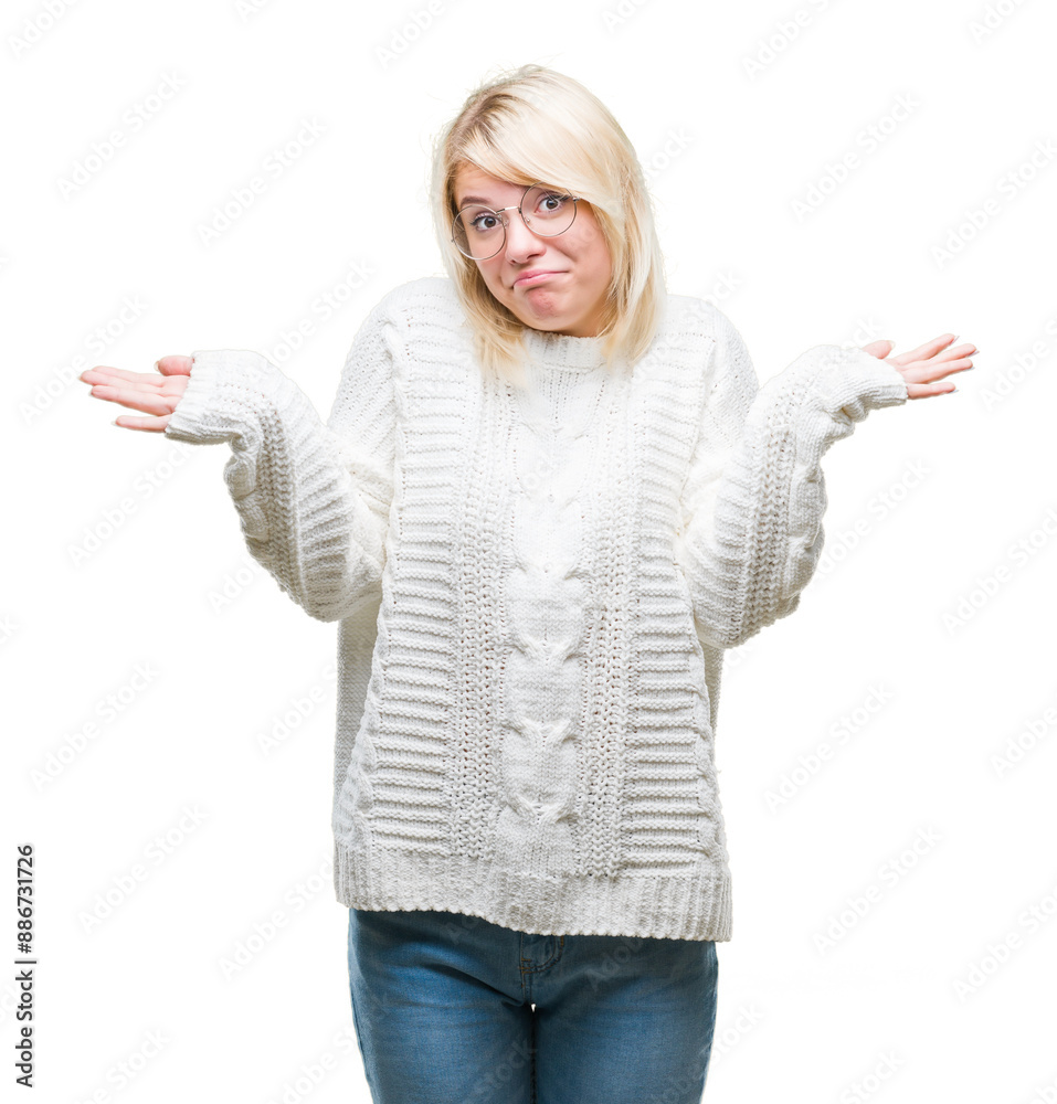 Young beautiful blonde woman wearing winter sweater and glasses over isolated background clueless and confused expression with arms and hands raised. Doubt concept. Young beautiful blonde woman wearing winter sweater and glasses over isolated background clueless and confused expression with arms and hands raised. Doubt concept.