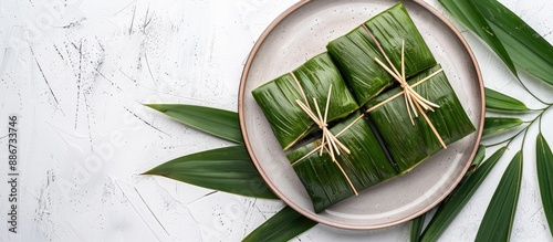 Traditional Chinese zongzies set on a plate with bamboo leaves for Dragon Boat Festival on a white background with a copy space image photo