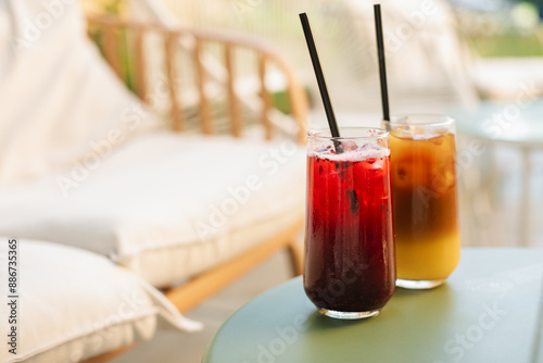Refreshing summer drinks in tall glasses with straws on the table, on the summer terrace.