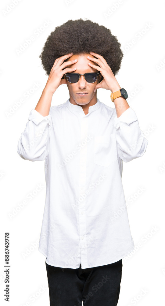 Young african american man with afro hair wearing sunglasses suffering from headache desperate and stressed because pain and migraine. Hands on head. Young african american man with afro hair wearing sunglasses suffering from headache desperate and stressed because pain and migraine. Hands on head.